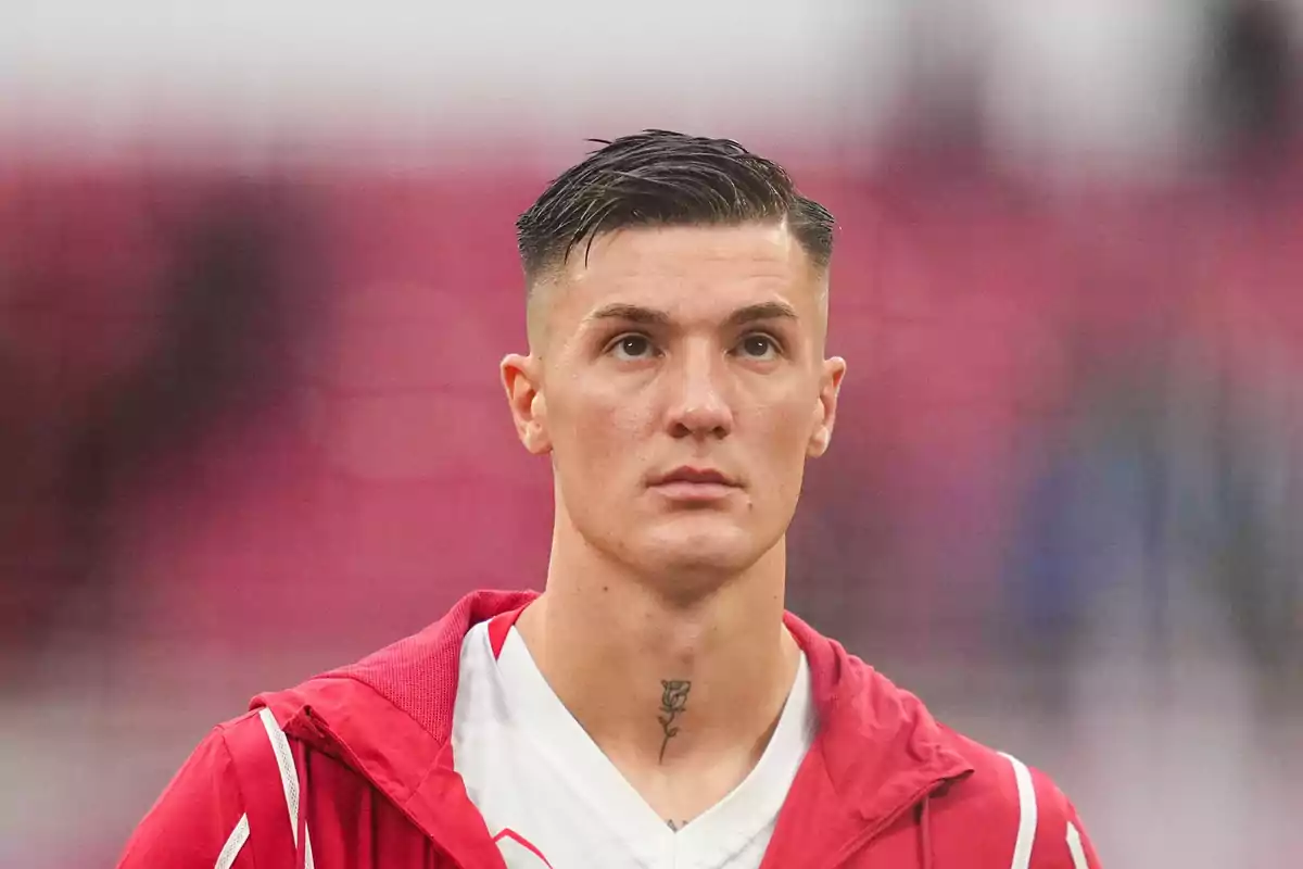 Joven con chaqueta roja y camiseta blanca mirando al frente con fondo desenfocado rojo Joven con chaqueta roja y camiseta blanca mirando al frente con fondo desenfocado rojo