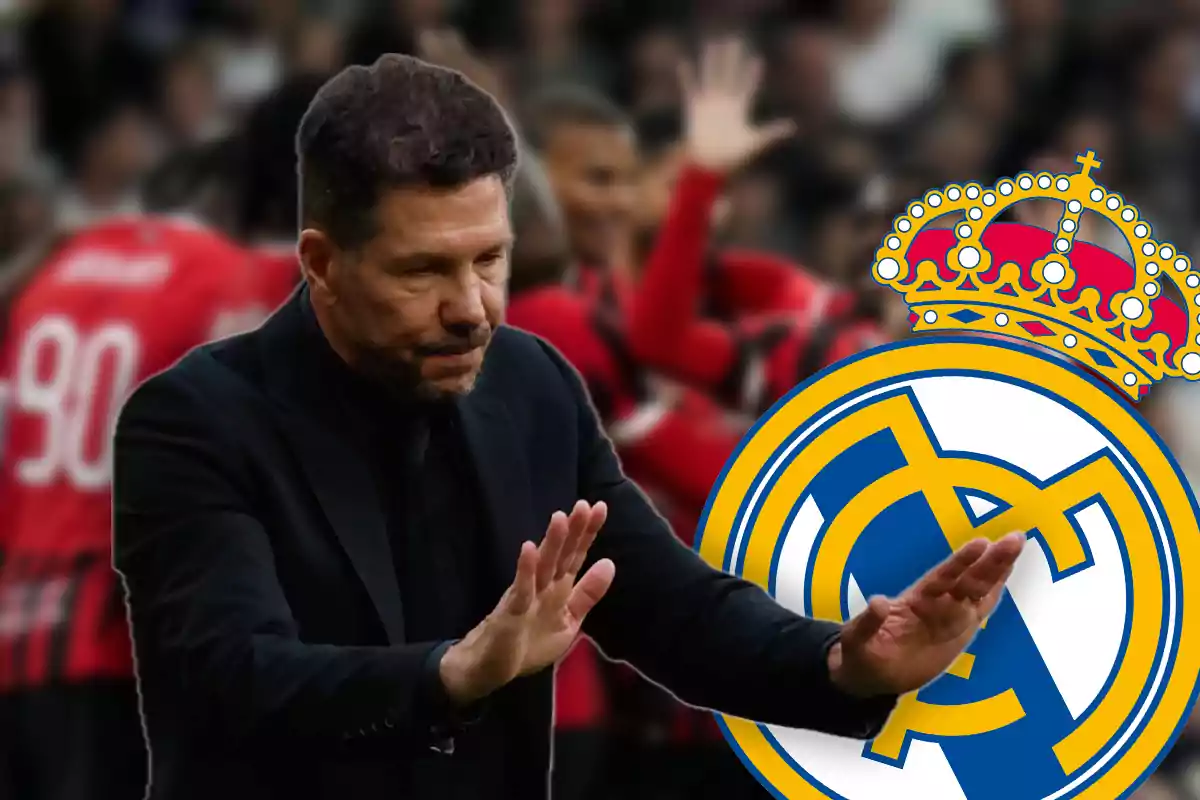 Entrenador de fútbol con gesto de calma frente al escudo del Real Madrid y jugadores desenfocados al fondo