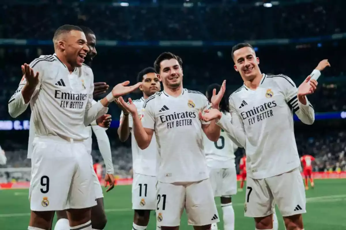 Jugadores de fútbol del Real Madrid celebrando en el campo con sonrisas y gestos de alegría.