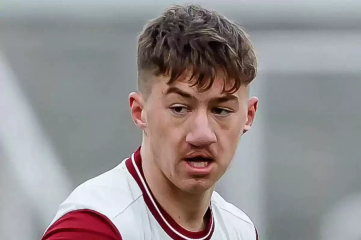 Joven con camiseta deportiva blanca y detalles en rojo durante un partido de fútbol Joven con camiseta deportiva blanca y detalles en rojo durante un partido de fútbol