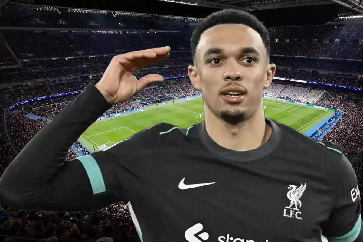 Football player in black Liverpool FC uniform in a stadium full of spectators.