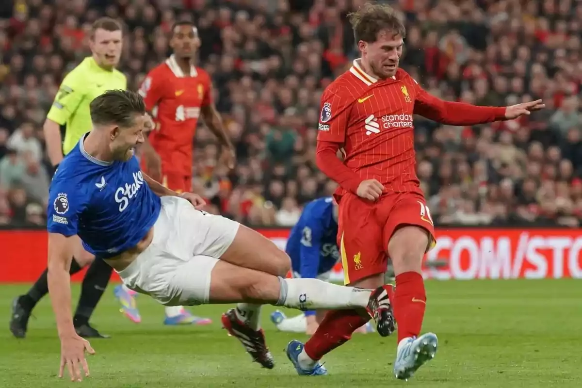 Two players compete for the ball in a match, one of them is making a sliding tackle while the other tries to maintain control. Two players compete for the ball in a match, one of them is making a sliding tackle while the other tries to maintain control.