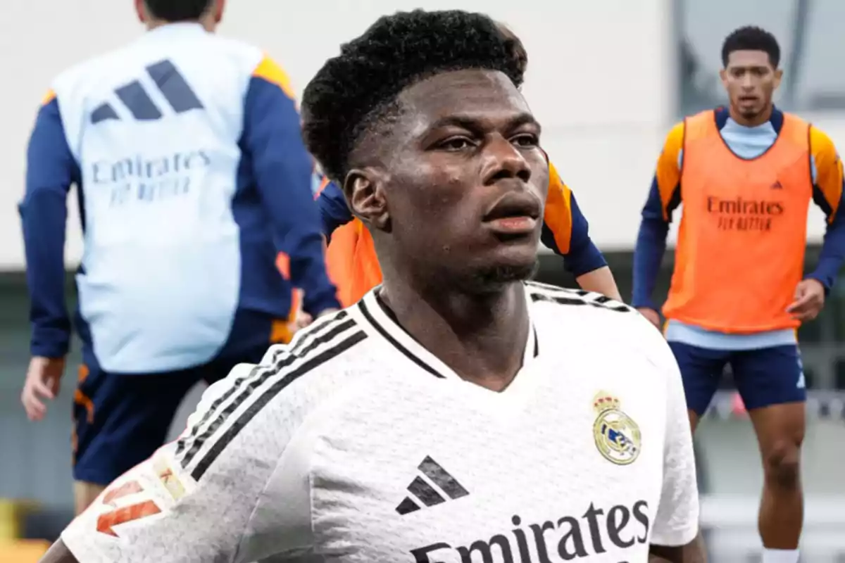 A Real Madrid soccer player in a white uniform in the foreground, while other players train in the background.