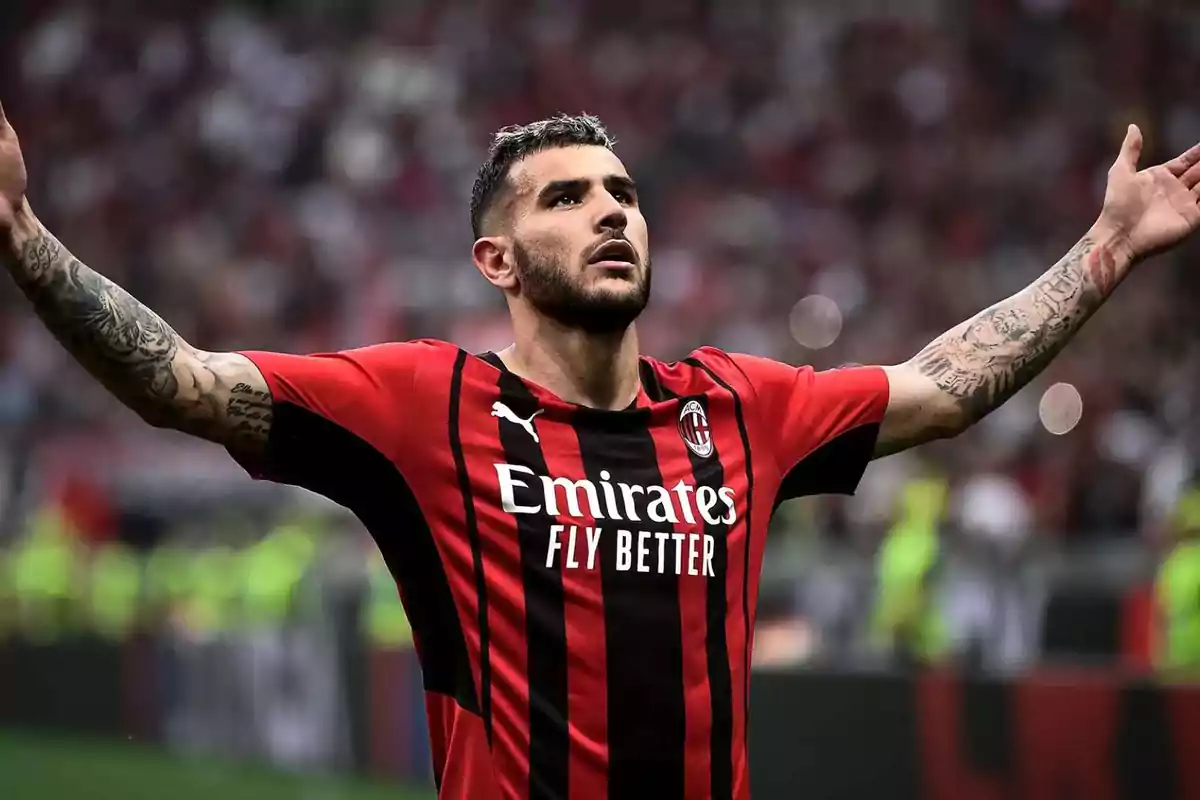 Soccer player in red and black uniform celebrating with open arms in a stadium.