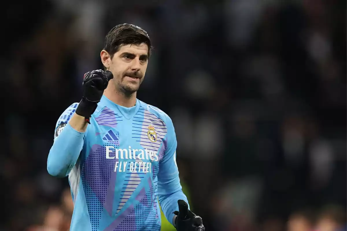 Real Madrid goalkeeper in a blue uniform raising his fist in celebration during a soccer match Real Madrid goalkeeper in a blue uniform raising his fist in celebration during a soccer match