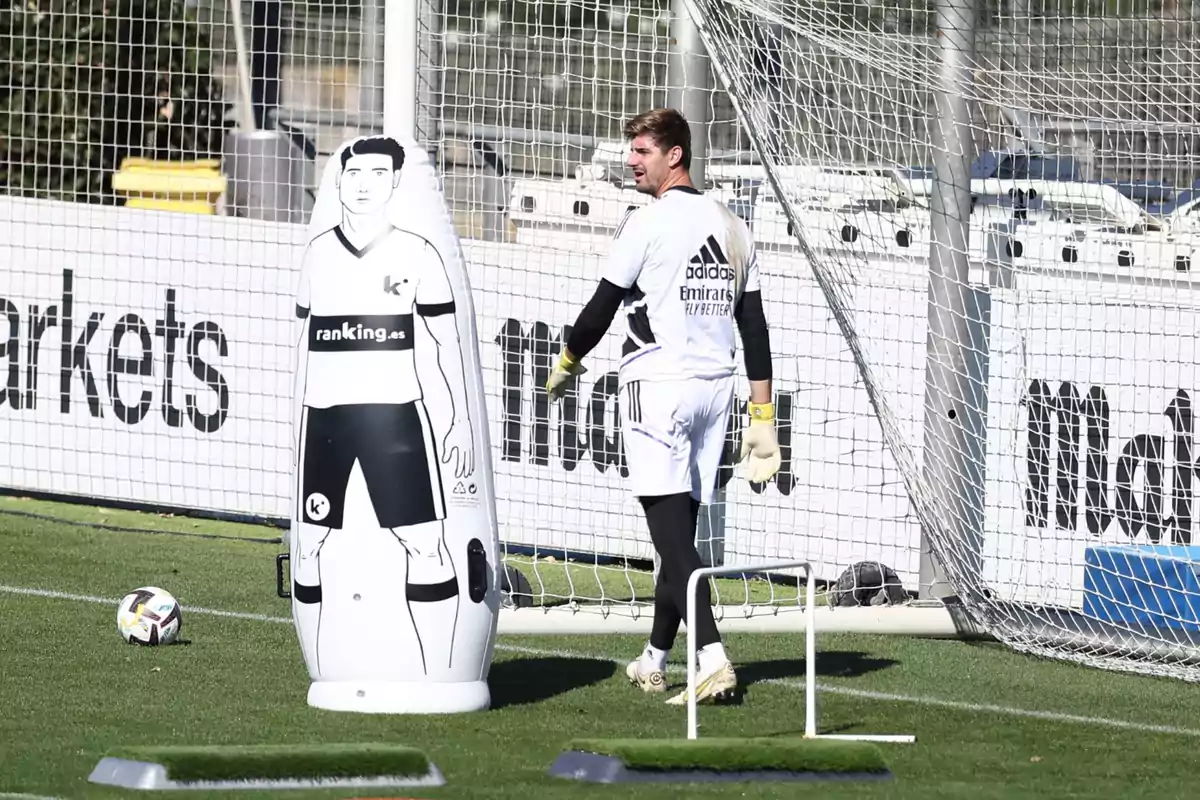 Portero entrenando en un campo de fútbol junto a un maniquí inflable y una portería