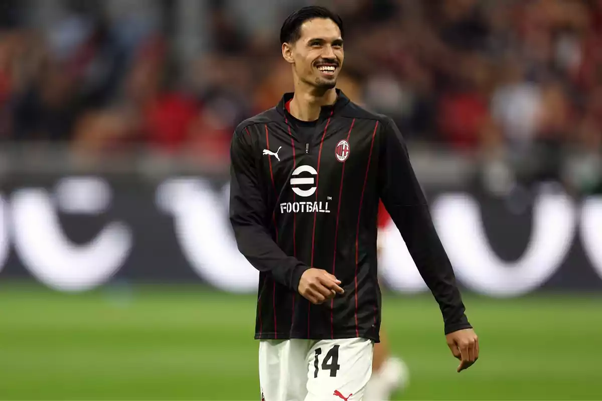 Un jugador de fútbol con uniforme negro y rojo del AC Milan sonríe en el campo. Un jugador de fútbol con uniforme negro y rojo del AC Milan sonríe en el campo.