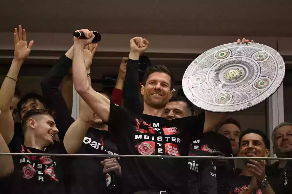 Entrenador de fútbol celebrando con su equipo y levantando un trofeo de campeón rodeado de jugadores sonrientes Entrenador de fútbol celebrando con su equipo y levantando un trofeo de campeón rodeado de jugadores sonrientes