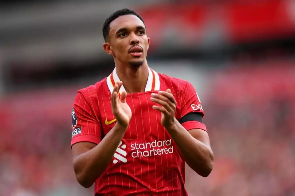 Football player in red uniform applauding on the field.