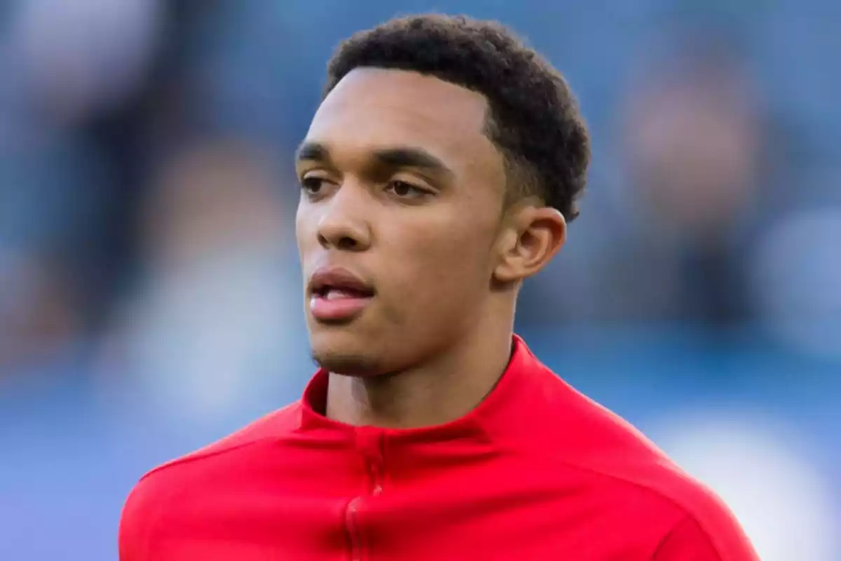 Un hombre joven con chaqueta roja en un campo de fútbol.