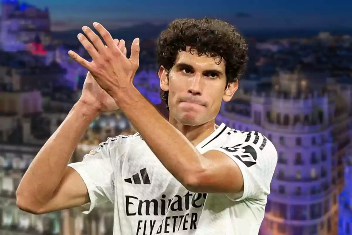 A player in a white uniform claps with a blurred urban background.