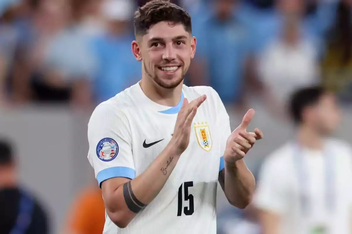 Un jugador de fútbol con la camiseta de Uruguay aplaudiendo en el campo.