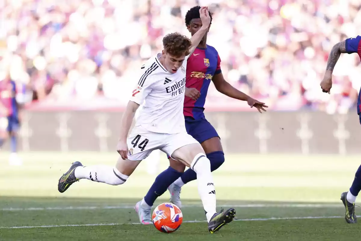 Real Madrid player tries to kick the ball while being pressured by a Barcelona player during a soccer match. Real Madrid player tries to kick the ball while being pressured by a Barcelona player during a soccer match.
