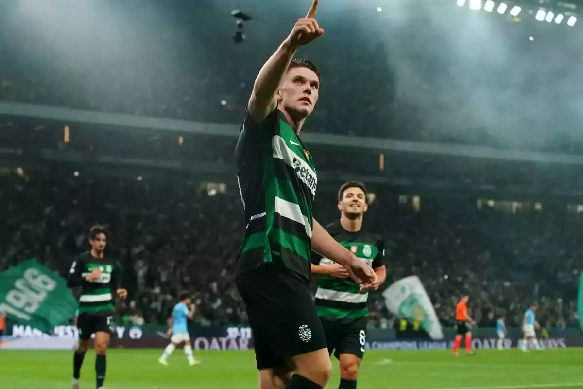 Futbolista del Sporting de Lisboa celebrando un gol en un estadio lleno de aficionados mientras señala hacia arriba Futbolista del Sporting de Lisboa celebrando un gol en un estadio lleno de aficionados mientras señala hacia arriba