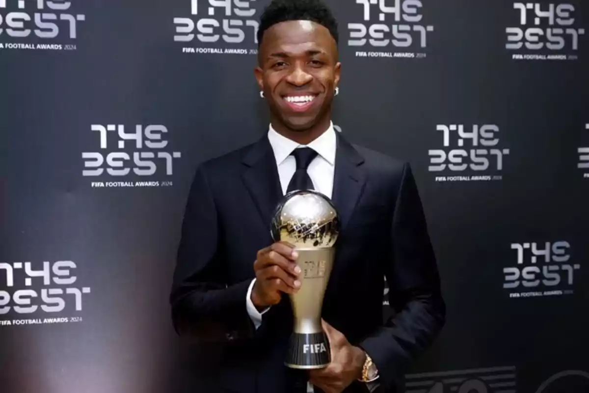 Person smiling while holding a trophy at a soccer awards event with a background that says Person smiling while holding a trophy at a soccer awards event with a background that says