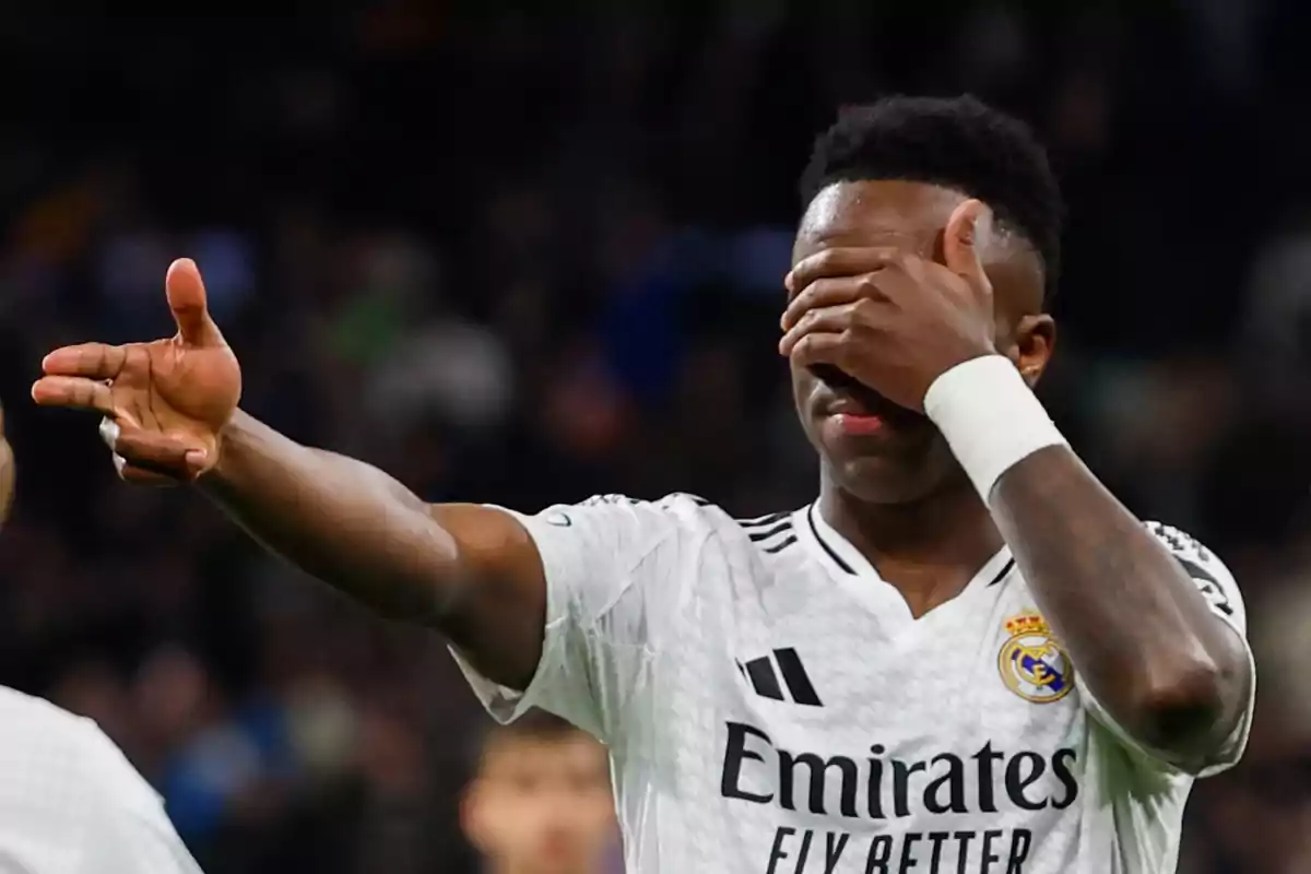 A player wearing a Real Madrid jersey covers his eyes with one hand while extending the other forward in a gesture. A player wearing a Real Madrid jersey covers his eyes with one hand while extending the other forward in a gesture.