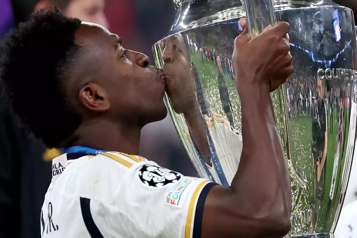 A player kisses a large silver trophy in celebration.