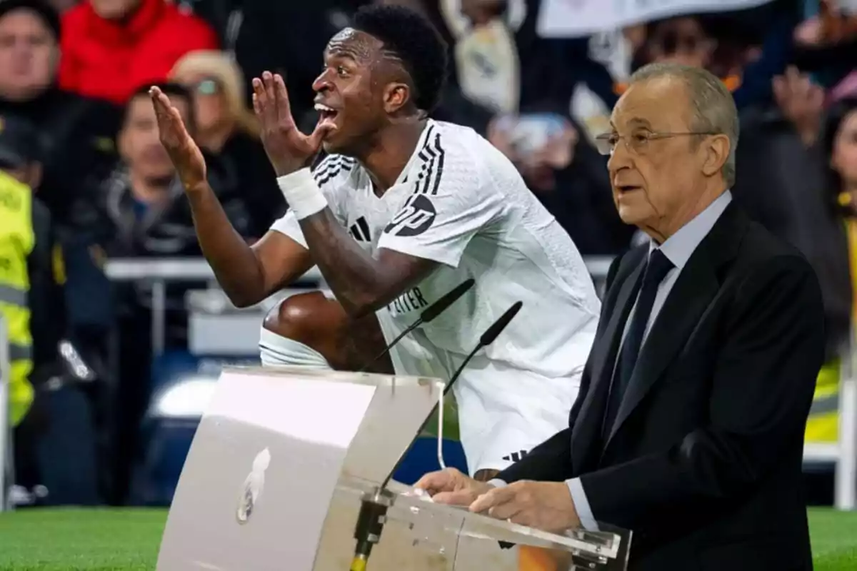 A player in a white uniform gestures passionately while an older person in a suit speaks from a podium.