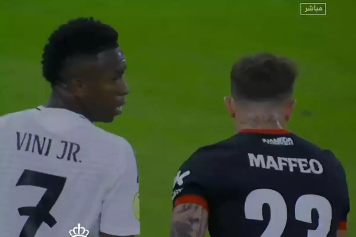 Dos jugadores de fútbol conversan en el campo durante un partido.