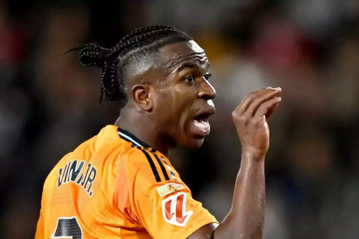 A soccer player in an orange uniform gestures during a match. A soccer player in an orange uniform gestures during a match.