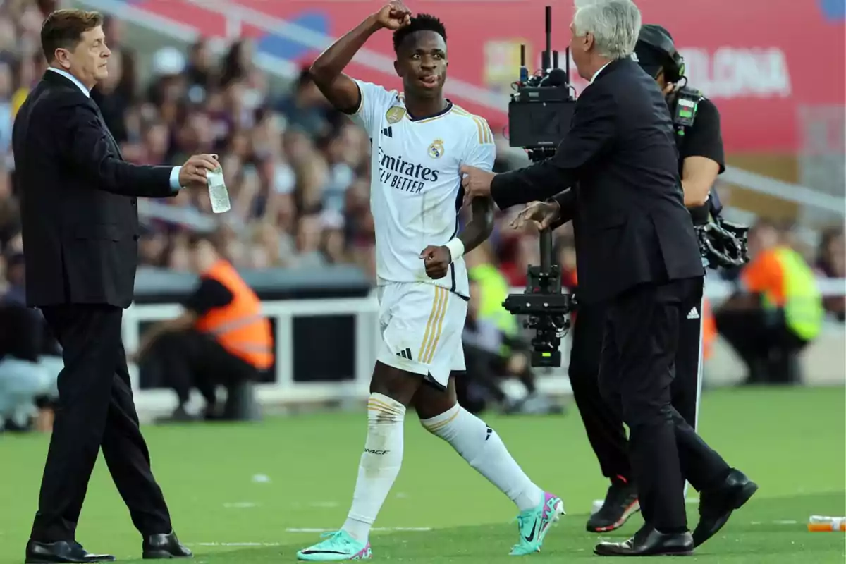 A Real Madrid football player interacts with the coaching staff and a cameraman on the field during a match.