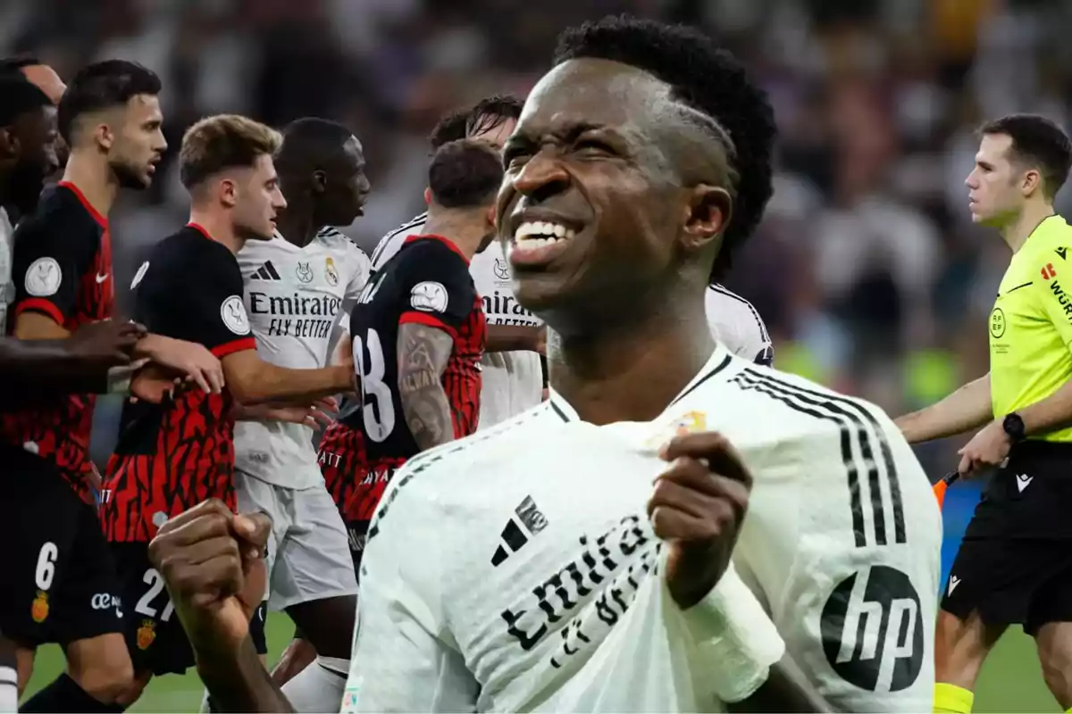 Un jugador de fútbol del Real Madrid celebra con emoción mientras otros jugadores y un árbitro están en el fondo del campo.