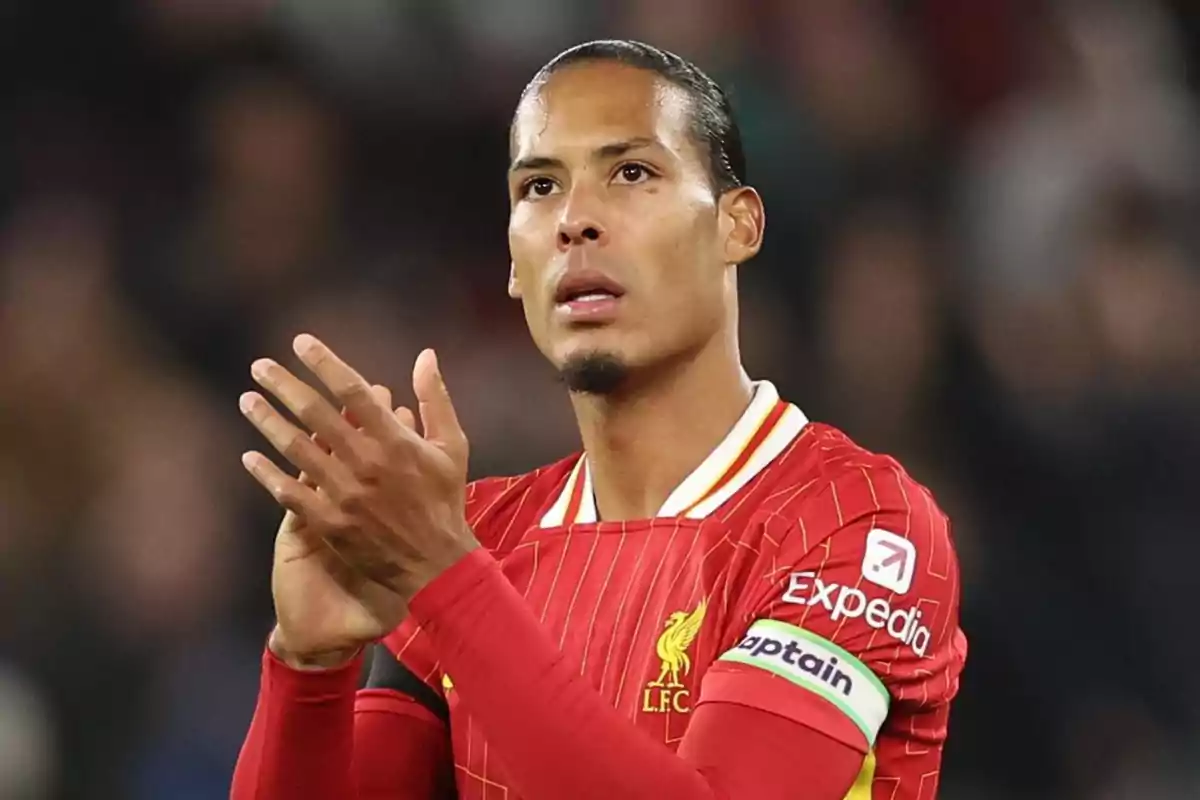 Un jugador de fútbol con uniforme rojo aplaude en el campo.