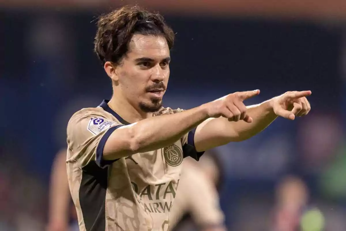 A soccer player in a beige uniform points forward during a game. A soccer player in a beige uniform points forward during a game.