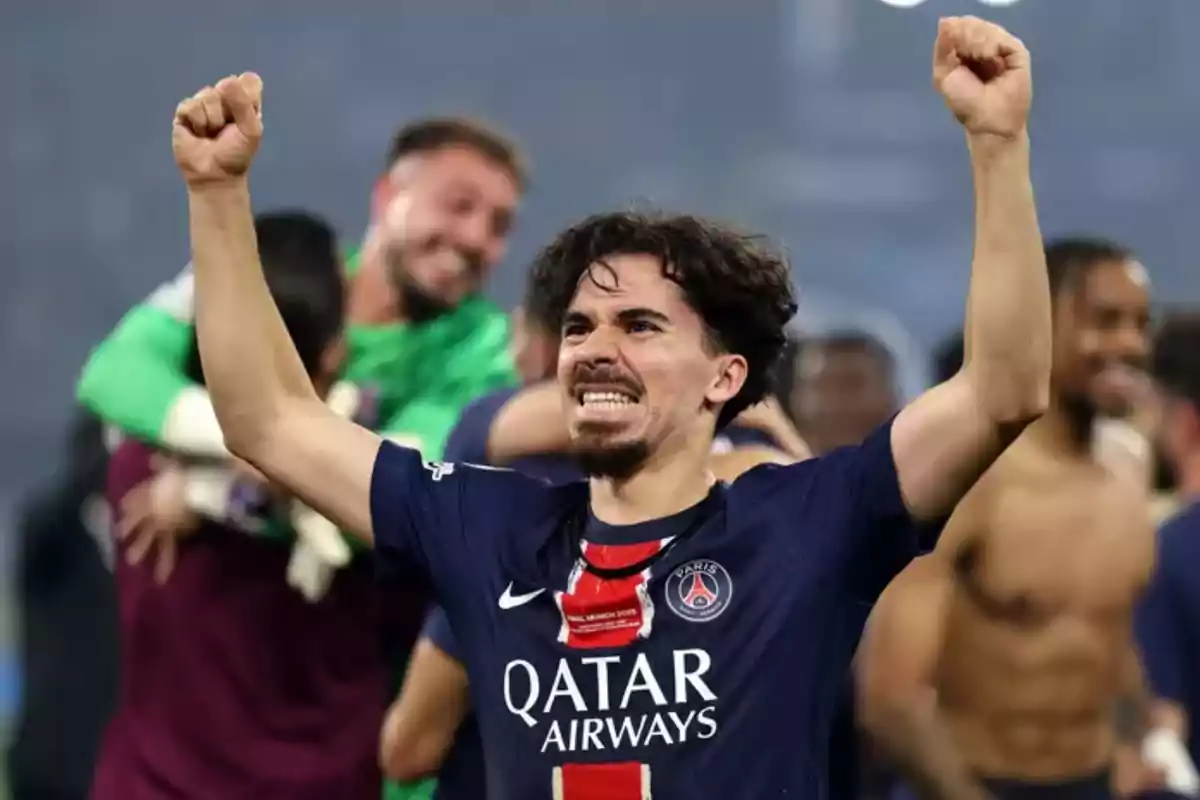Futbolista del PSG celebrando con los brazos en alto mientras sus compañeros festejan al fondo Futbolista del PSG celebrando con los brazos en alto mientras sus compañeros festejan al fondo