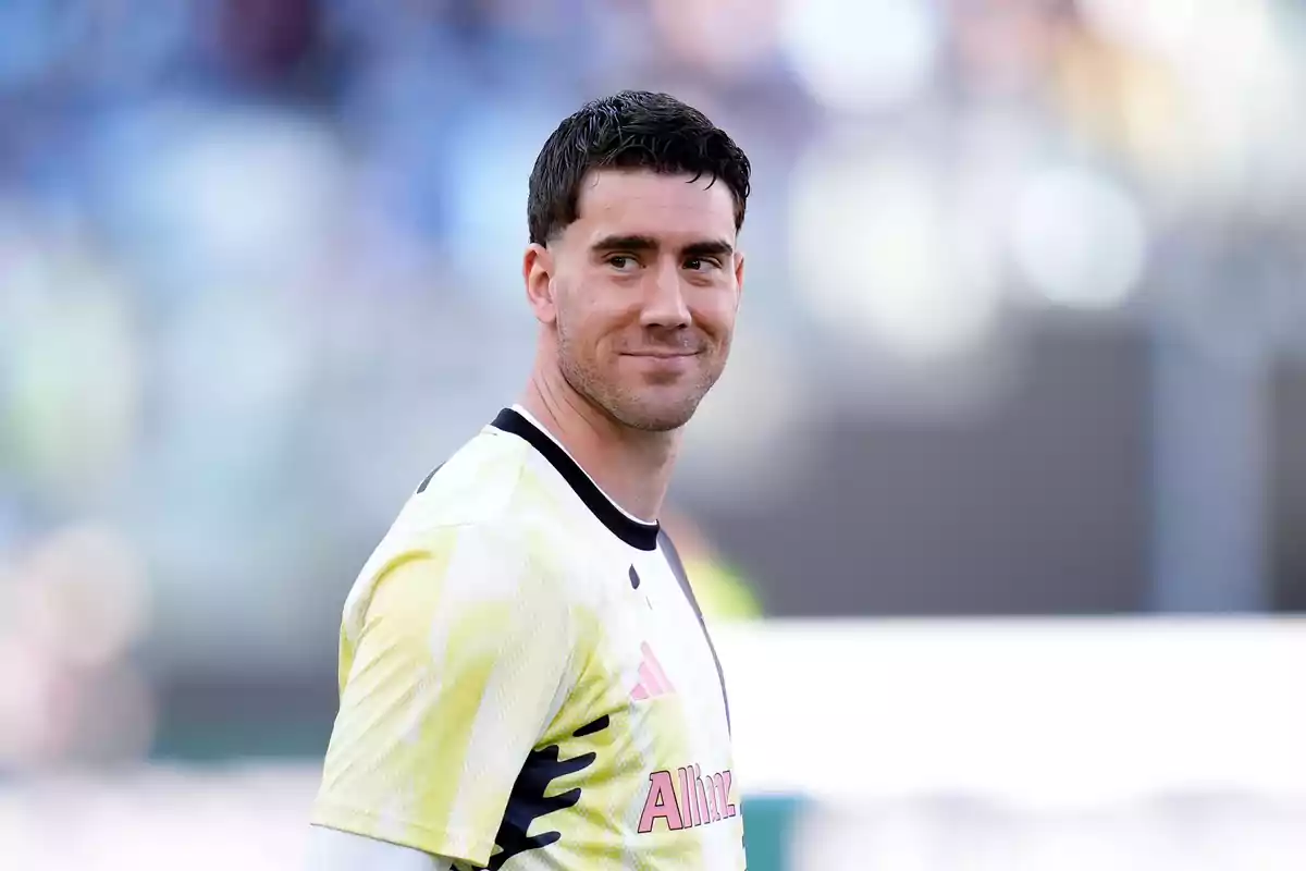 Soccer player wearing a white and yellow training jersey smiling in a stadium Soccer player wearing a white and yellow training jersey smiling in a stadium