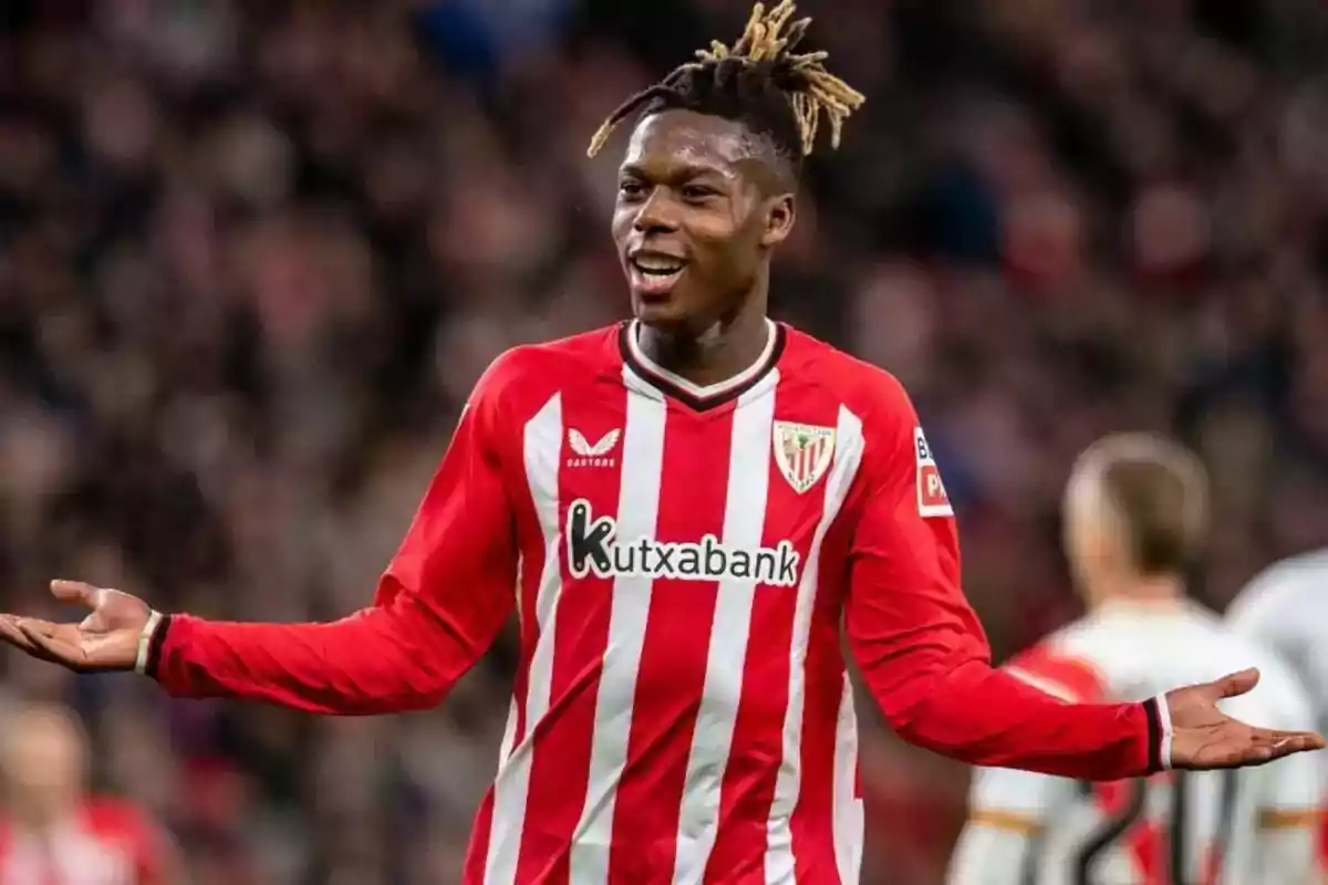 A player in the Athletic Club de Bilbao uniform gestures with open arms during a match. A player in the Athletic Club de Bilbao uniform gestures with open arms during a match.