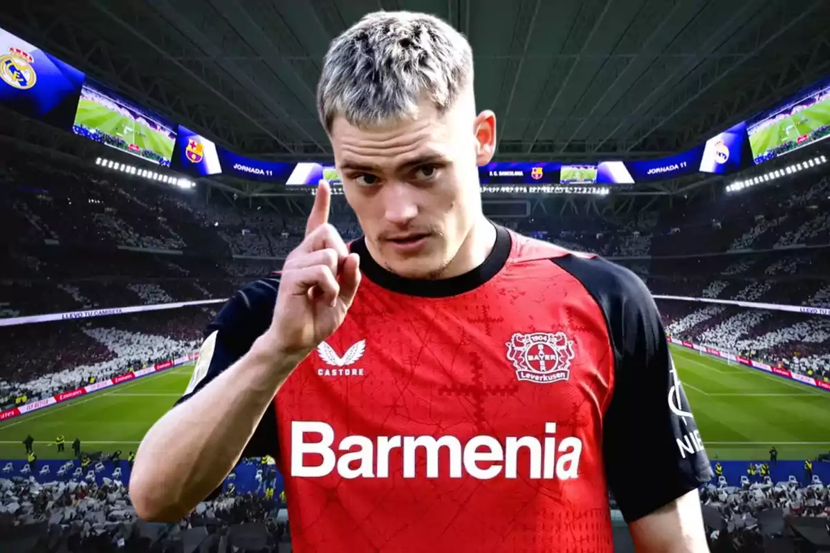 A player wearing a Bayer Leverkusen jersey is in a stadium full of spectators, pointing upward with his index finger.
