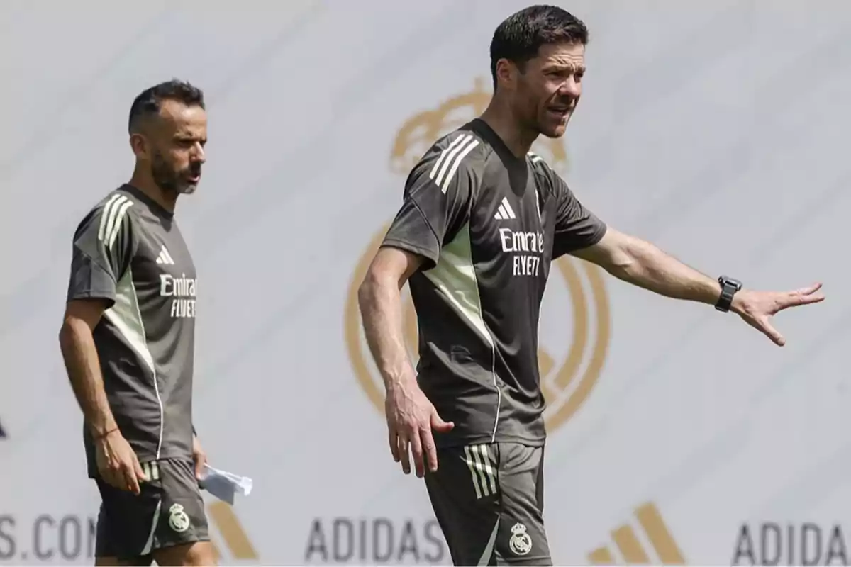 Dos entrenadores con uniforme de entrenamiento del Real Madrid dan indicaciones en un campo de fútbol Dos entrenadores con uniforme de entrenamiento del Real Madrid dan indicaciones en un campo de fútbol