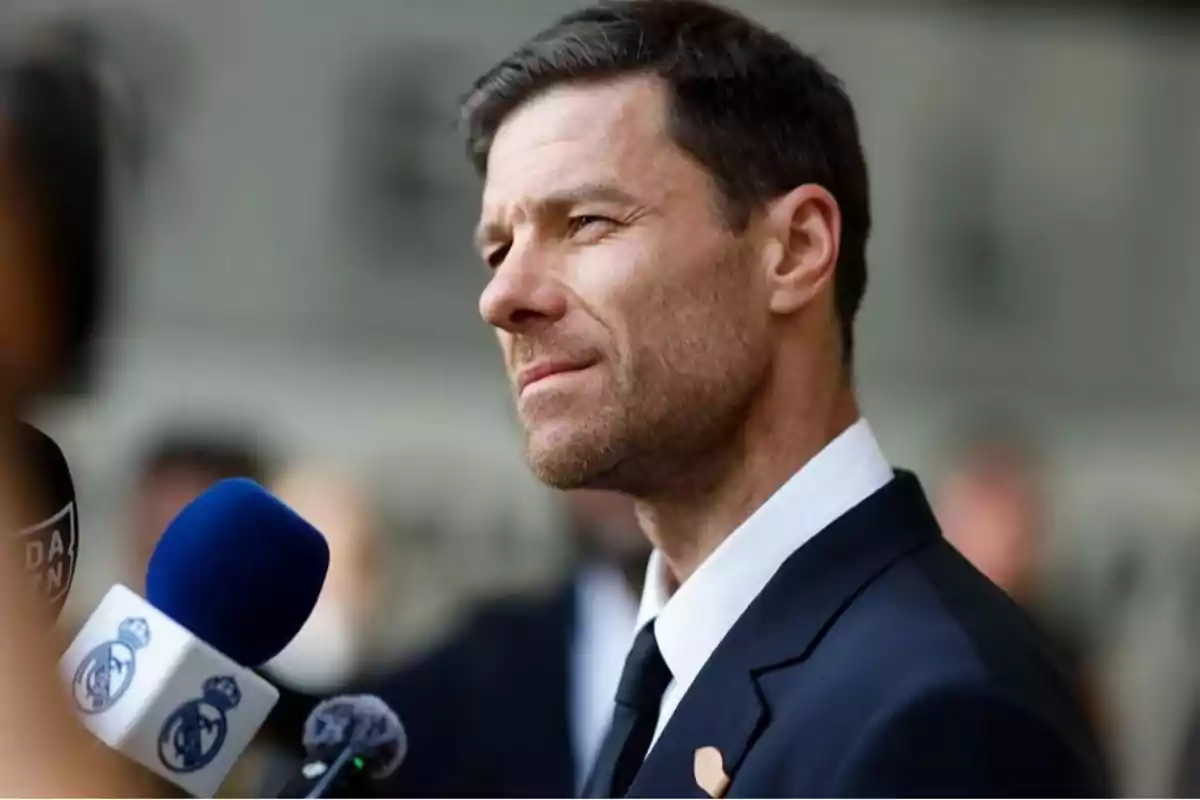 Man in a dark suit being interviewed by several microphones Man in a dark suit being interviewed by several microphones
