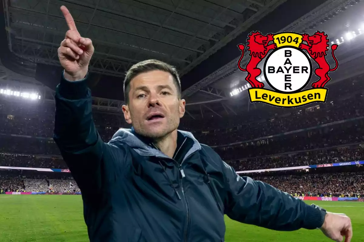A soccer coach in a stadium full of spectators with the Bayer Leverkusen logo in the top right corner.