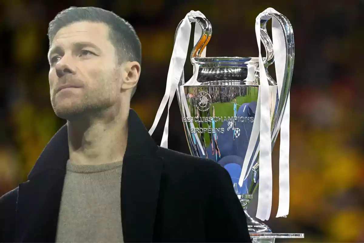 Short-haired man with a beard looking up with the Champions League trophy in the background