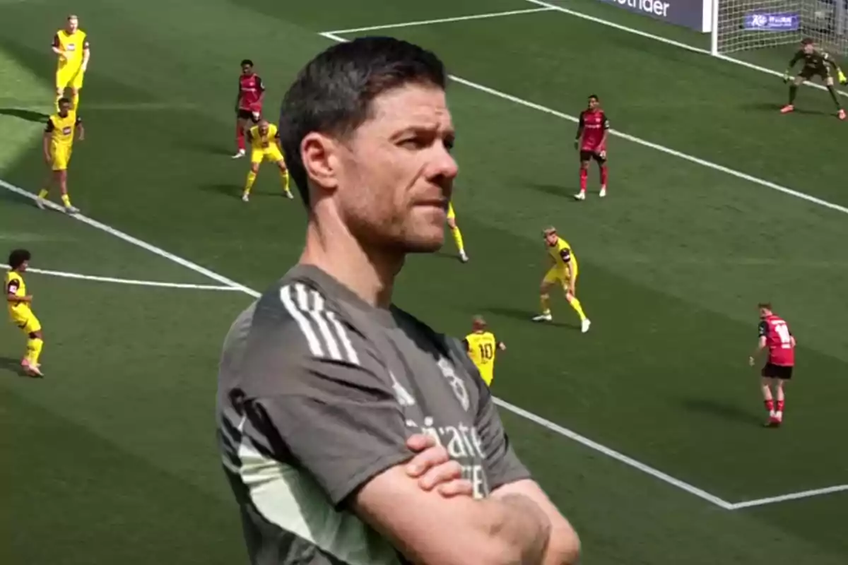 Soccer coach with arms crossed watching a game while several players are in the box during a play