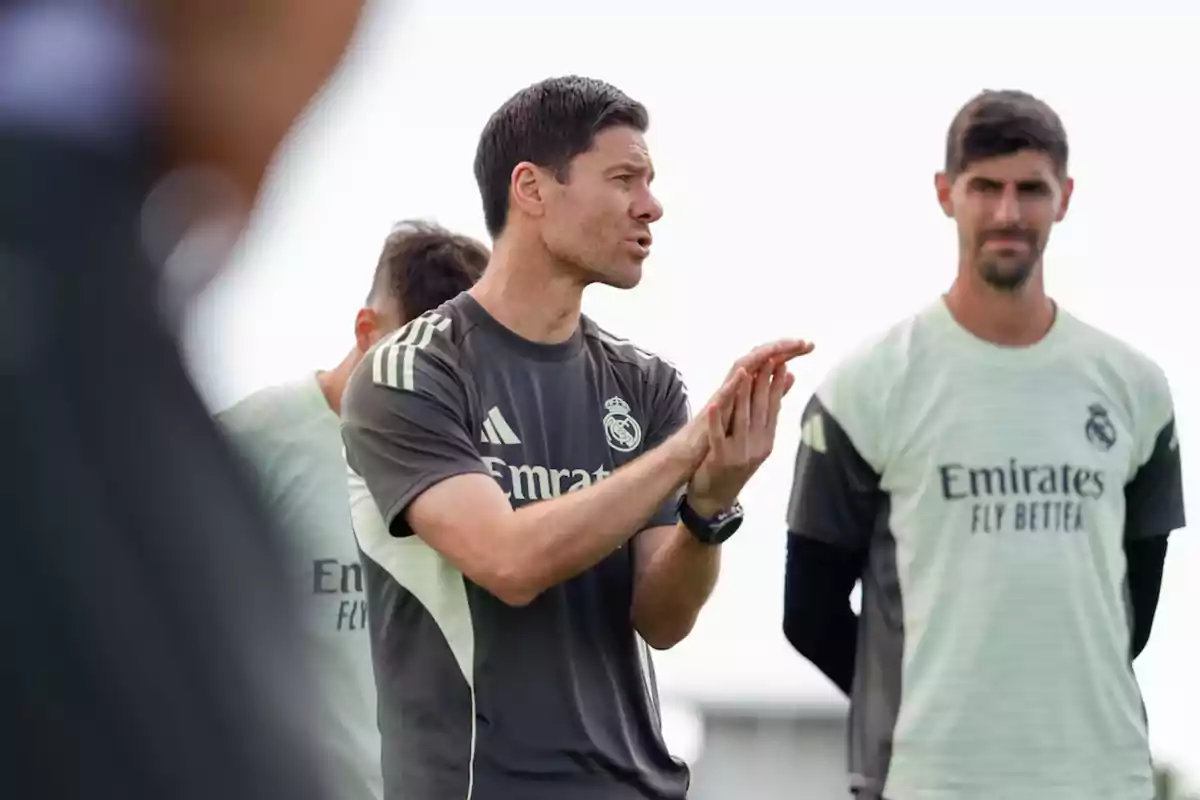 Entrenador del Real Madrid dando indicaciones durante una sesión de entrenamiento con jugadores atentos al fondo Entrenador del Real Madrid dando indicaciones durante una sesión de entrenamiento con jugadores atentos al fondo