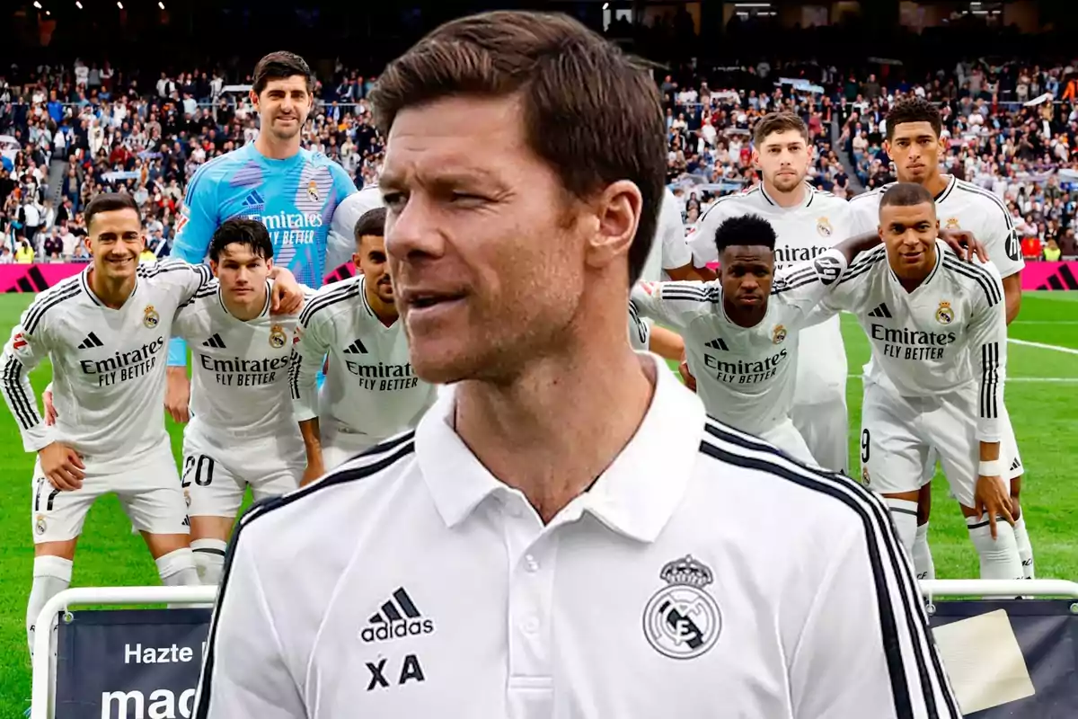Un entrenador del Real Madrid aparece en primer plano mientras el equipo posa para una foto grupal en el estadio con la afición de fondo