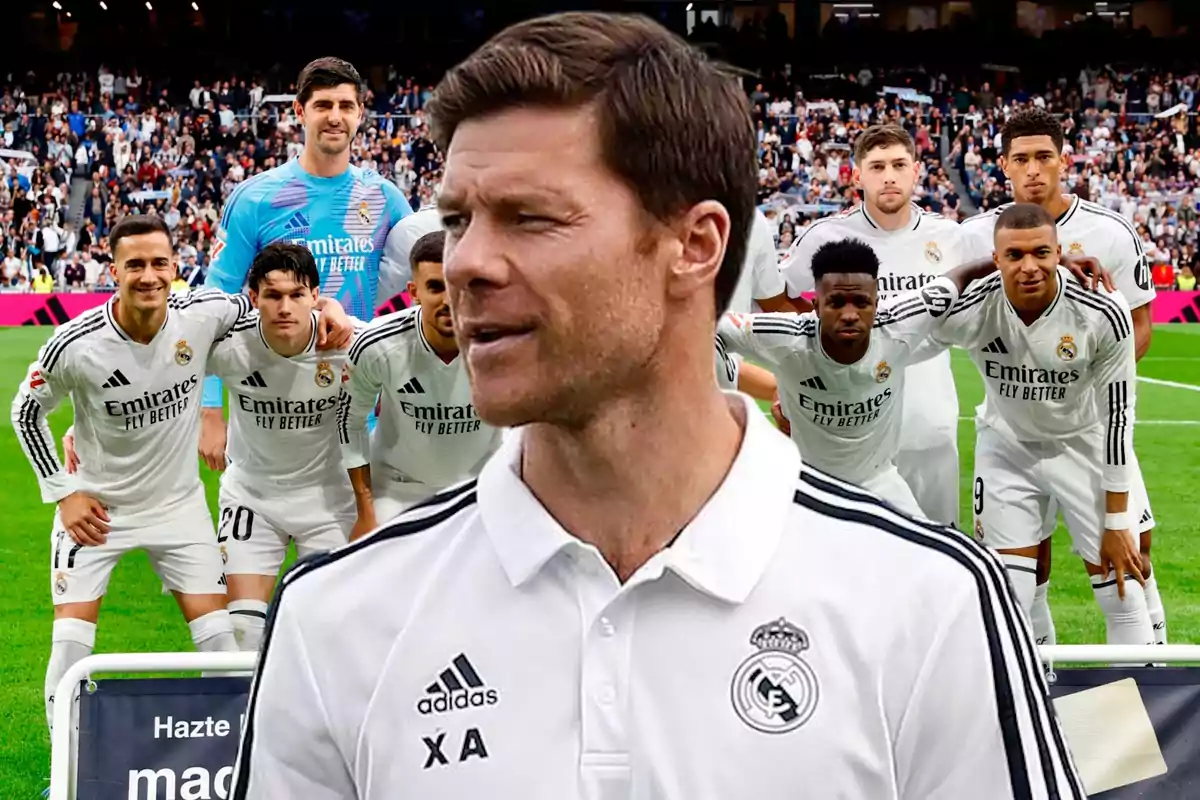 Un entrenador del Real Madrid aparece en primer plano con el equipo posando en el campo de fútbol y el estadio lleno de aficionados al fondo
