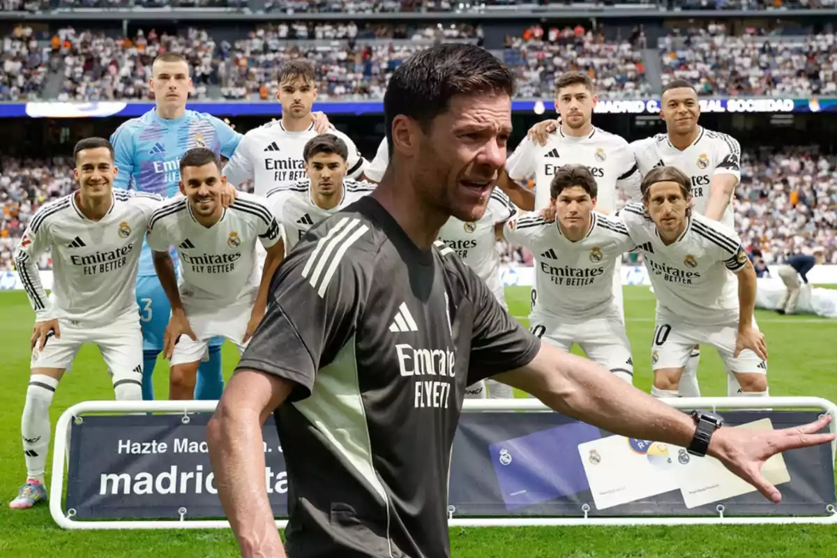 Un entrenador de fútbol da indicaciones en primer plano mientras un equipo vestido de blanco posa para la foto oficial en el estadio lleno de aficionados.
