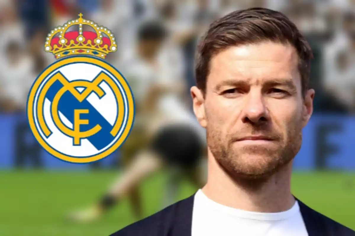 A brown-haired man with a beard is standing in front of a blurred background with the Real Madrid crest beside him.