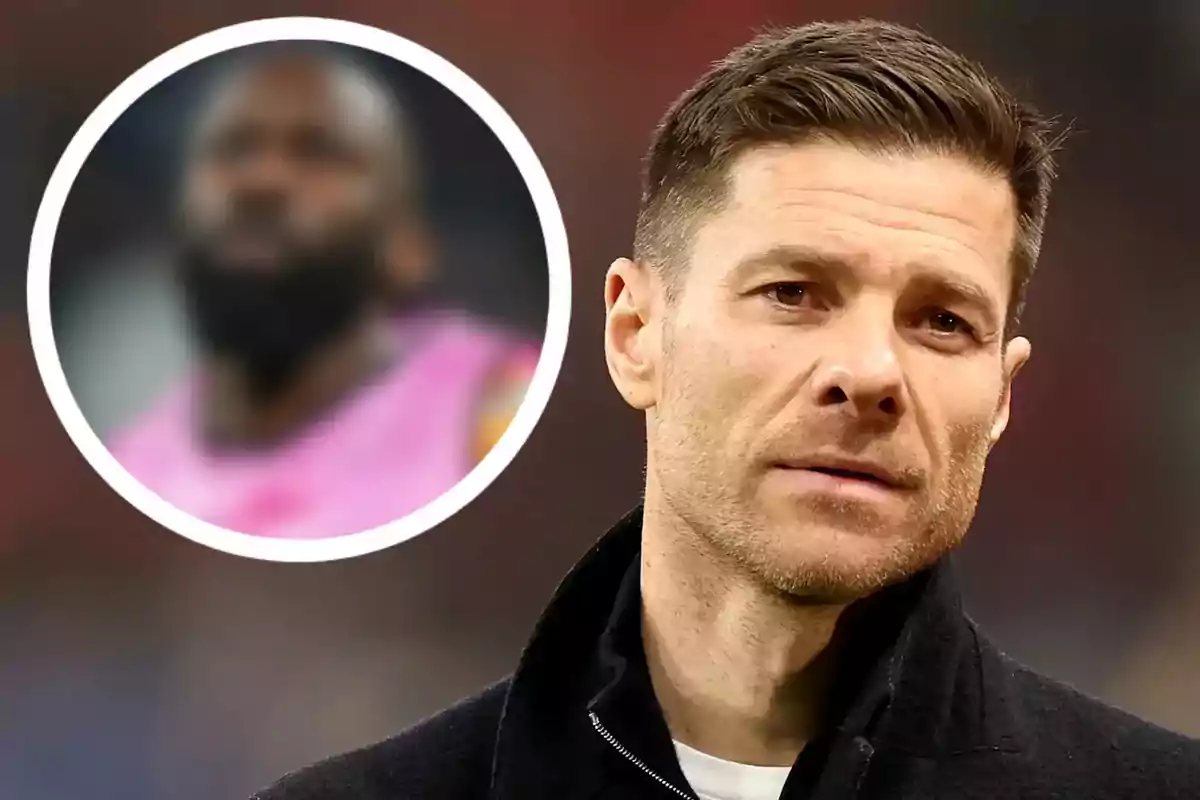 Short-haired man with a light beard in the foreground with a serious expression; in the background, there is a circle with the blurred image of another person.