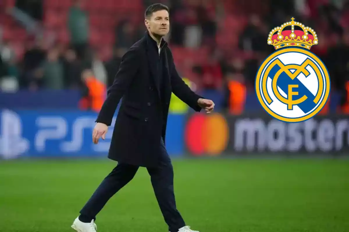 A man walking on a soccer field with the Real Madrid logo in the corner.