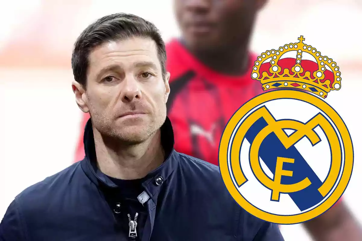 Un hombre con chaqueta oscura junto al escudo del Real Madrid.