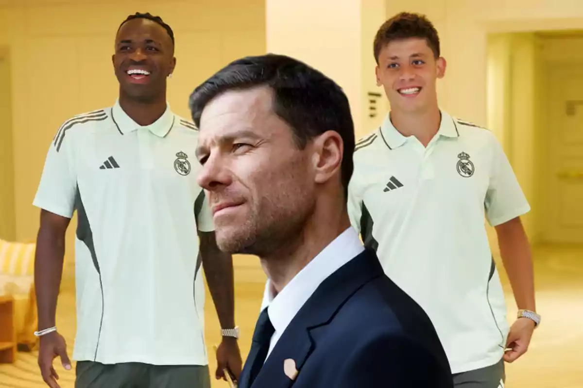 Tres personas, dos con uniforme deportivo del Real Madrid y una con traje, posan en un ambiente interior iluminado.