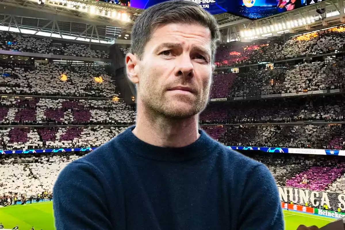 Short-haired man with a light beard wearing a dark sweater in a football stadium full of fans