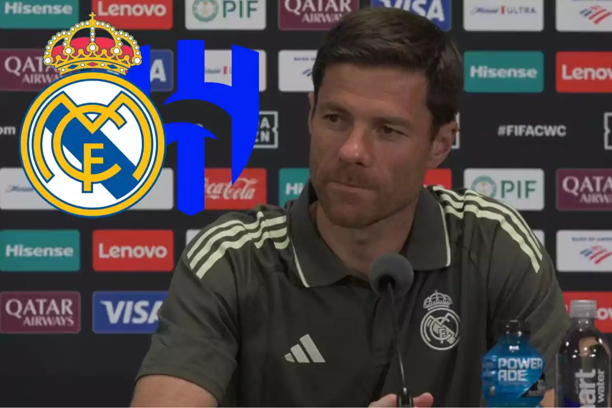Real Madrid coach at a press conference with Real Madrid and a blue team logos in the background