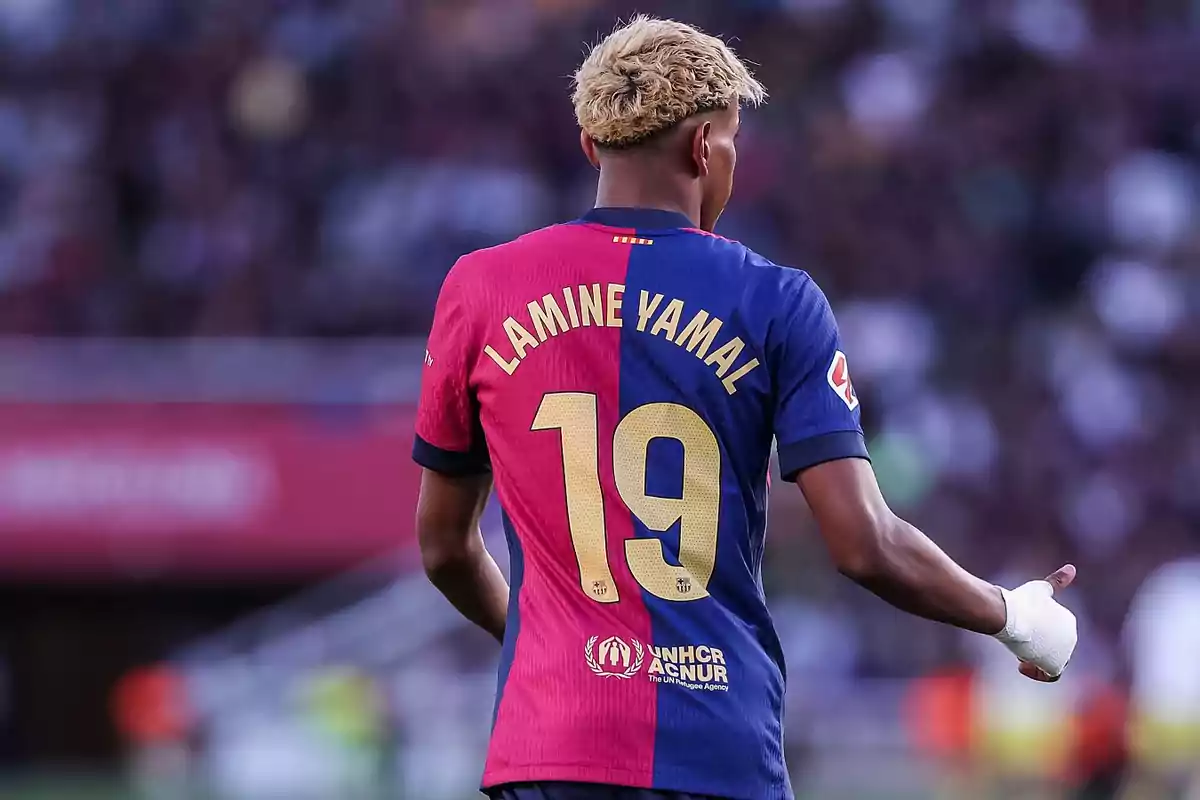 Jugador de fútbol con el dorsal 19 y el nombre Lamine Yamal en la camiseta del FC Barcelona visto de espaldas en un estadio Jugador de fútbol con el dorsal 19 y el nombre Lamine Yamal en la camiseta del FC Barcelona visto de espaldas en un estadio