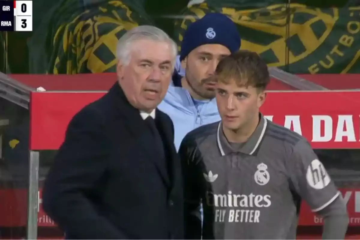 A Real Madrid coach and player stand on the touchline during a match against Girona, with the score showing 0-3 in favor of Real Madrid.